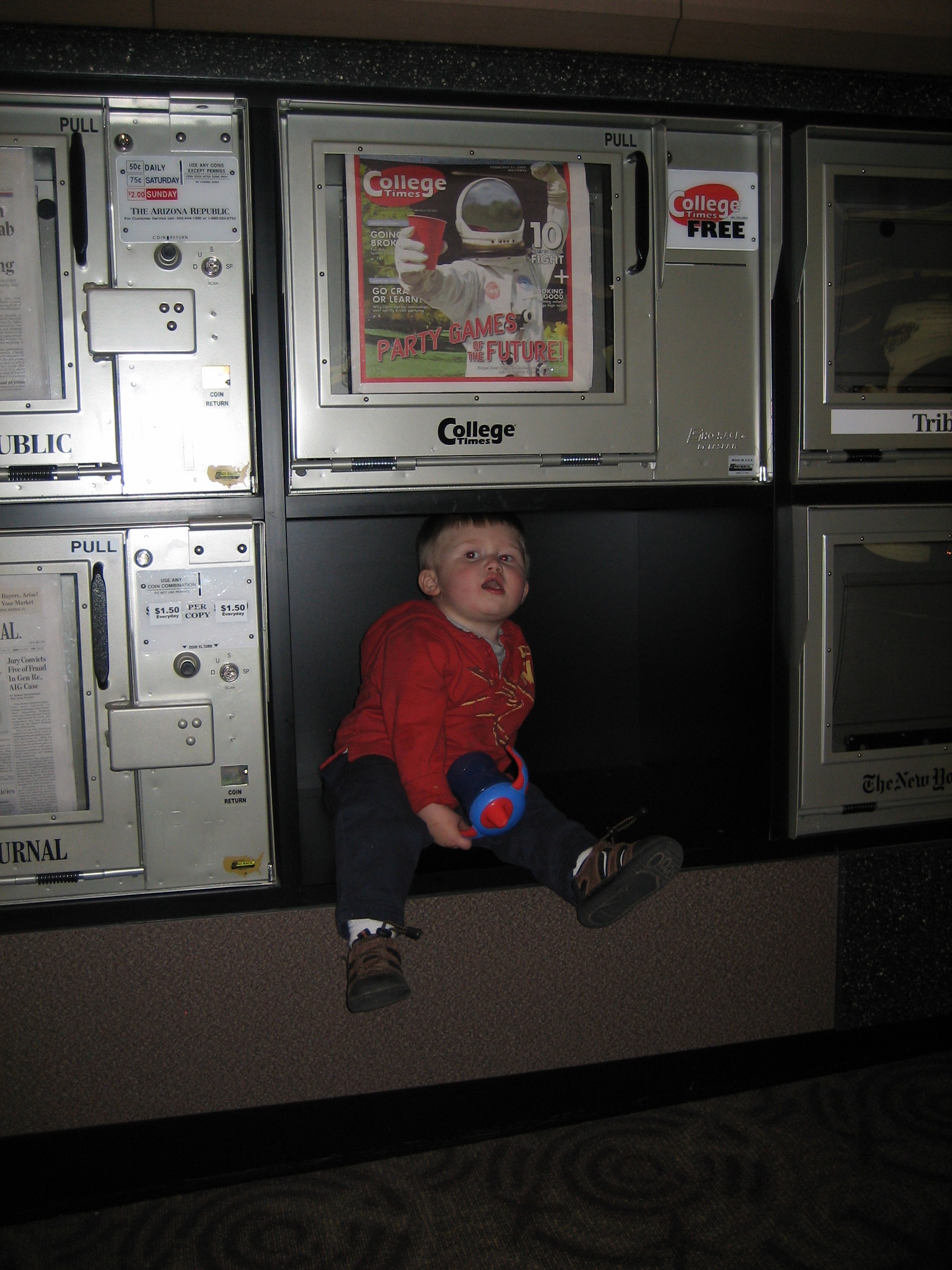 small child in a newspaper dispenser
